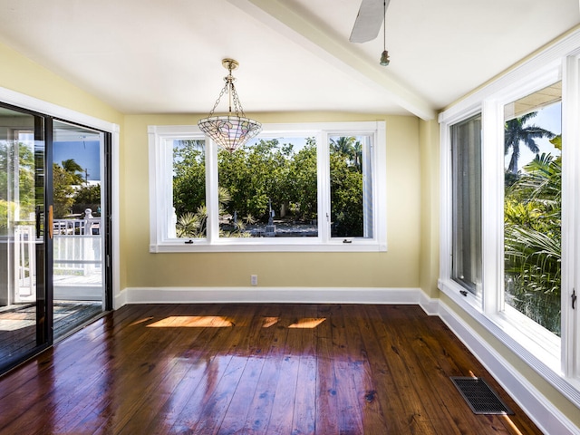 unfurnished dining area featuring dark wood-type flooring and beam ceiling