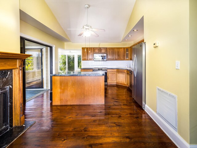 kitchen featuring stainless steel appliances, vaulted ceiling, tasteful backsplash, and dark wood-type flooring