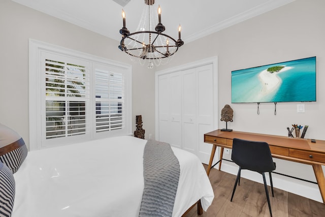 bedroom with hardwood / wood-style flooring, crown molding, a notable chandelier, and a closet