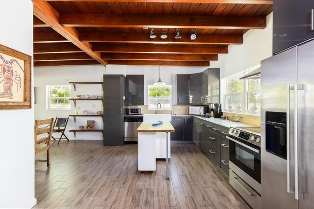 kitchen with butcher block counters, hanging light fixtures, gray cabinets, a kitchen island, and stainless steel appliances