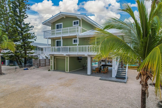 raised beach house with stairway, a balcony, and fence