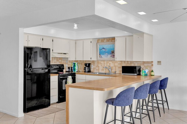 511 9th St, Key Colony, FL 33051 - kitchen featuring black appliances, under cabinet range hood, a sink, light tile patterned floors, and decorative backsplash