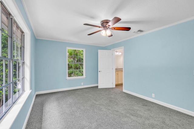 carpeted spare room featuring ornamental molding, plenty of natural light, and ceiling fan