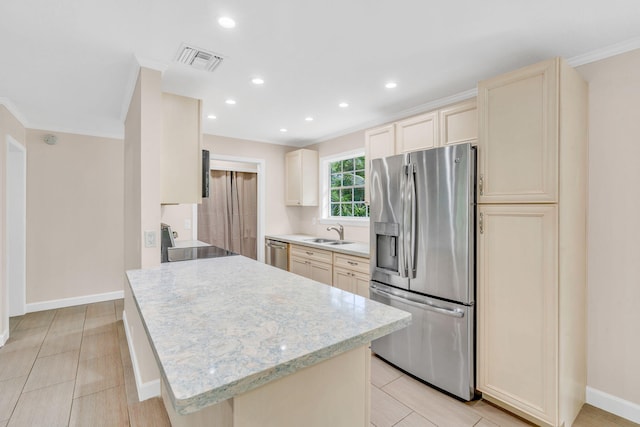 kitchen featuring sink, crown molding, light tile patterned floors, appliances with stainless steel finishes, and cream cabinets