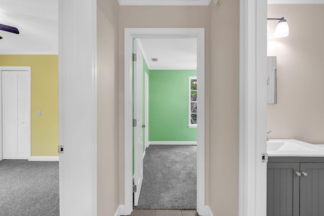 hall with light carpet, sink, and ornamental molding