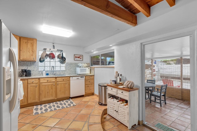 kitchen featuring sink, white appliances, beam ceiling, plenty of natural light, and decorative backsplash