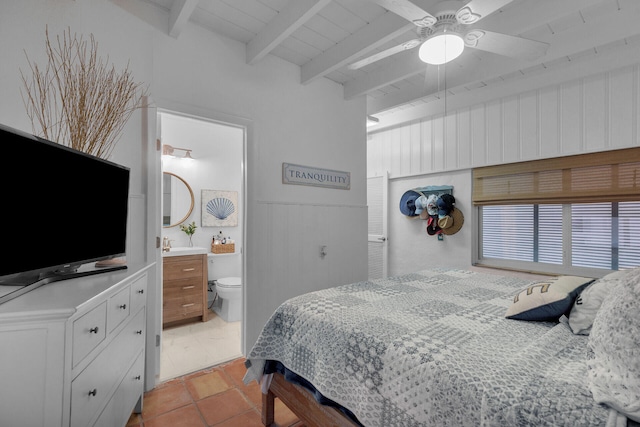 tiled bedroom featuring beam ceiling, ensuite bath, and ceiling fan