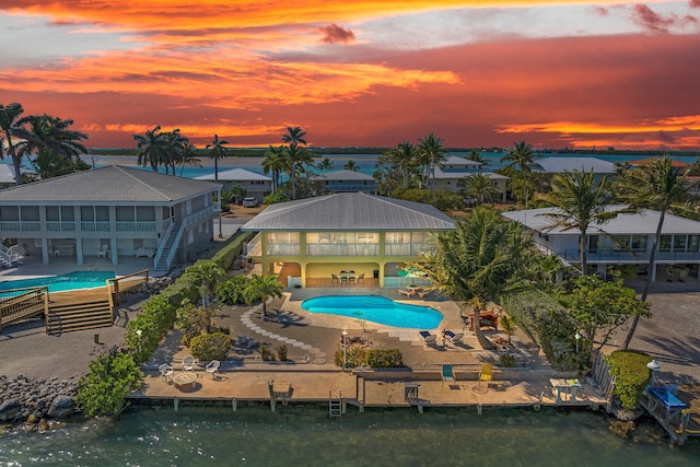 pool at dusk featuring a patio and a boat dock