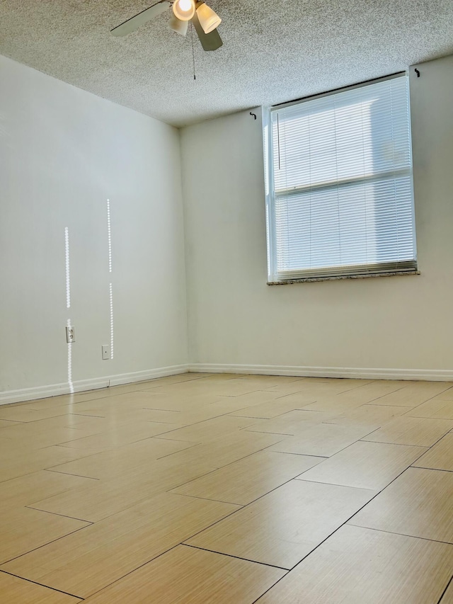 unfurnished room with ceiling fan and a textured ceiling