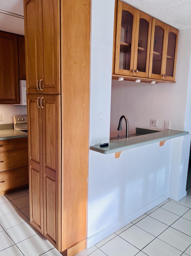 kitchen featuring light tile patterned flooring, sink, and a textured ceiling