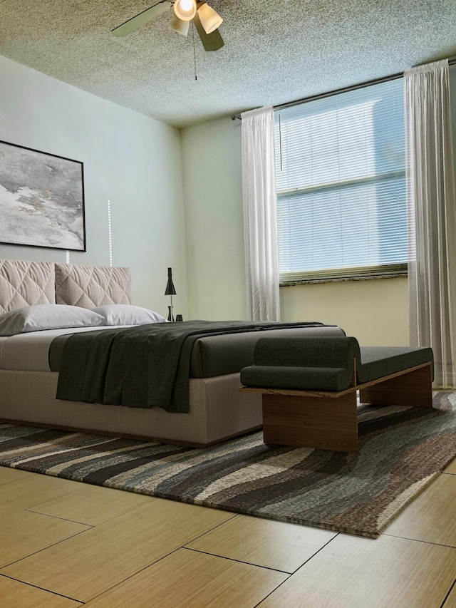 bedroom with hardwood / wood-style flooring, ceiling fan, and a textured ceiling