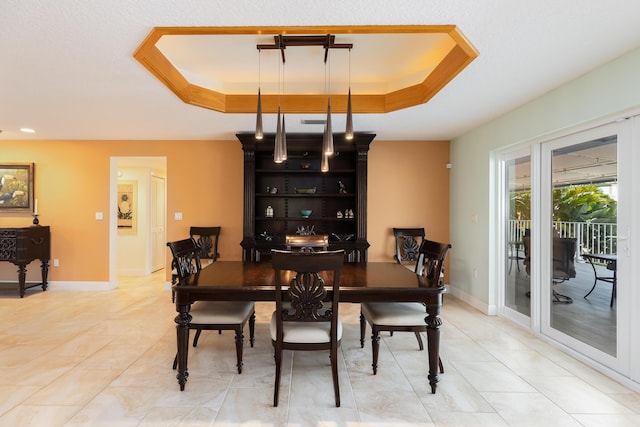 dining area featuring light tile patterned floors and a raised ceiling