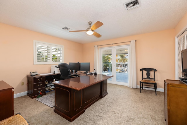 carpeted office space featuring ceiling fan, a healthy amount of sunlight, and a textured ceiling