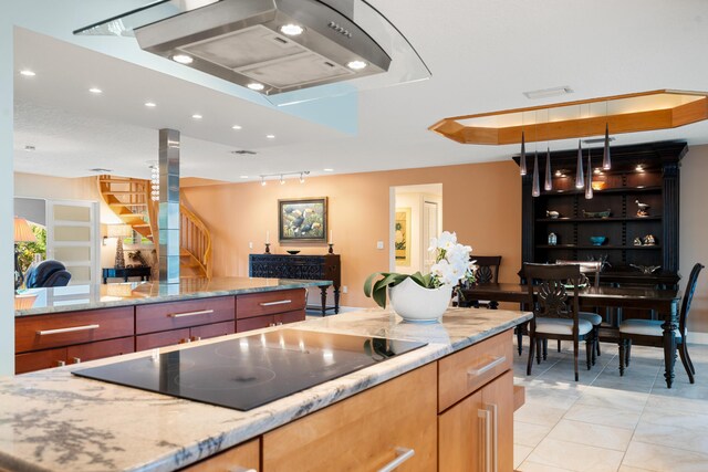 kitchen with black electric cooktop, hanging light fixtures, light tile patterned floors, and light stone countertops