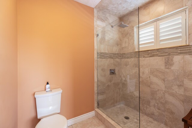 bathroom featuring toilet, tile patterned flooring, and a tile shower