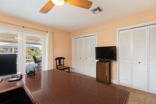 carpeted office space featuring a textured ceiling and ceiling fan