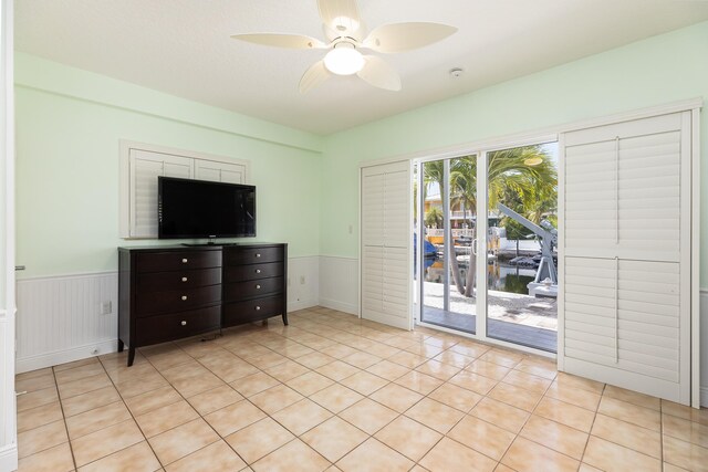 unfurnished bedroom with light tile patterned floors, access to exterior, and ceiling fan