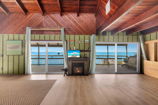 unfurnished living room with wooden walls, vaulted ceiling with beams, hardwood / wood-style floors, and wood ceiling