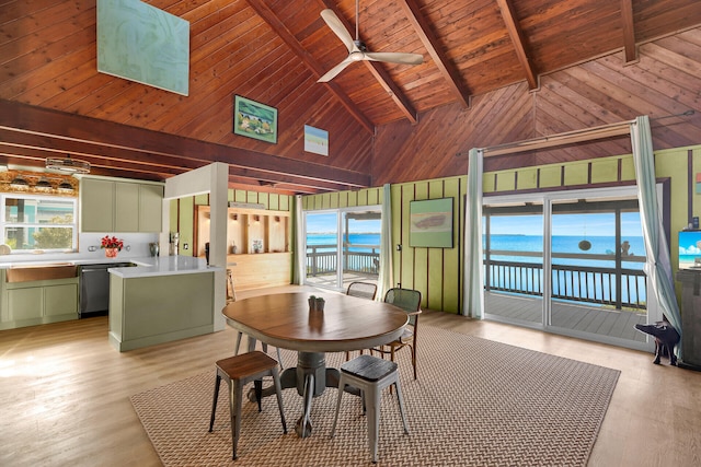 unfurnished dining area featuring a water view, wooden ceiling, light wood-type flooring, wooden walls, and ceiling fan