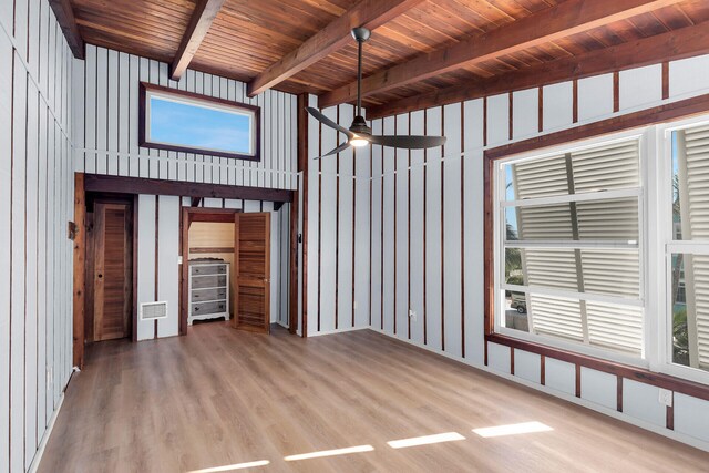 unfurnished sunroom featuring a healthy amount of sunlight, ceiling fan, wood ceiling, and beamed ceiling