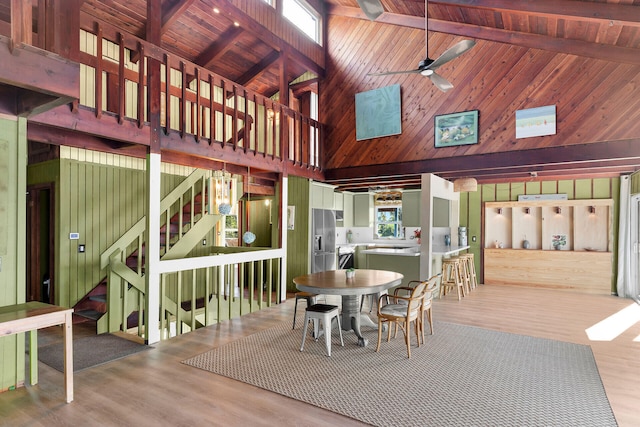 dining area featuring beamed ceiling, hardwood / wood-style floors, and wood walls