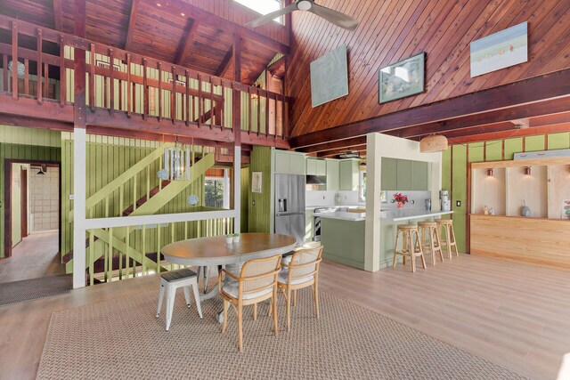 dining area featuring beam ceiling, wooden ceiling, ceiling fan, and light hardwood / wood-style floors