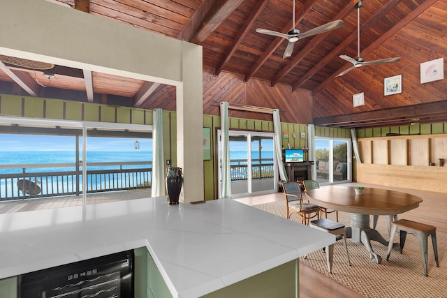 kitchen with green cabinetry, a water view, beverage cooler, and wood walls