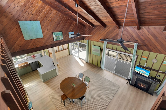 unfurnished living room with wood ceiling, wooden walls, light hardwood / wood-style floors, and lofted ceiling with beams