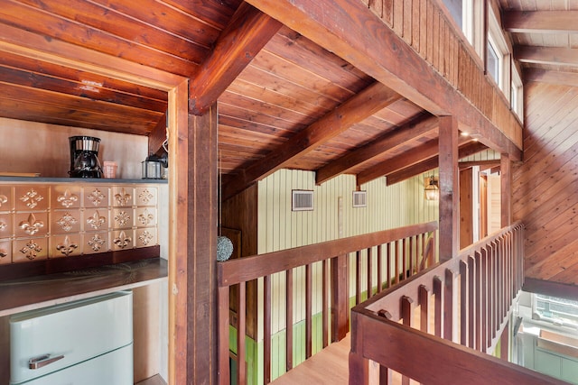 hallway featuring beam ceiling, wood ceiling, and wood walls