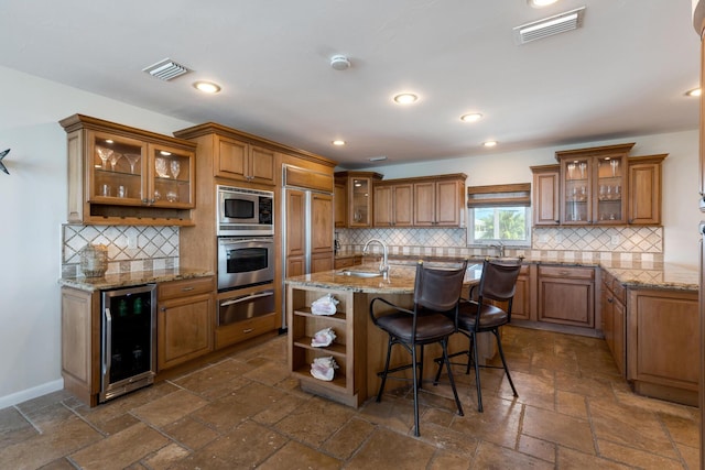 228 W Seaview Cir, Duck, FL 33050 - kitchen featuring beverage cooler, stainless steel appliances, brown cabinetry, a warming drawer, and stone tile flooring