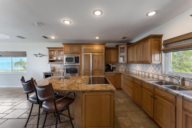 228 W Seaview Cir, Duck, FL 33050 - kitchen with a sink, built in appliances, brown cabinetry, stone tile flooring, and decorative backsplash