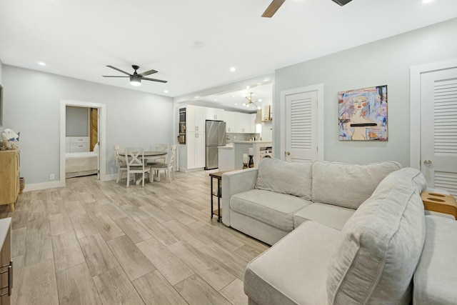 living area featuring ceiling fan with notable chandelier, light wood-type flooring, and recessed lighting