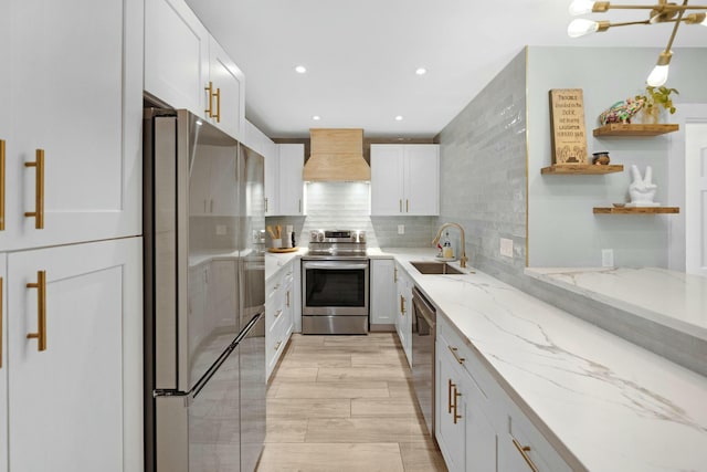 kitchen with custom exhaust hood, stainless steel appliances, tasteful backsplash, white cabinetry, and a sink