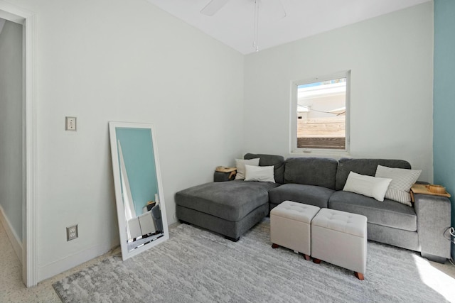 living area with baseboards and a ceiling fan