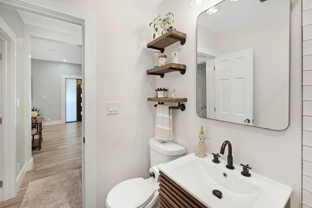 half bathroom with vanity, toilet, and wood finished floors