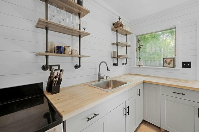 kitchen featuring range with electric cooktop, wooden counters, a sink, and open shelves