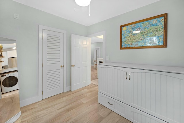 interior space with baseboards, washer / clothes dryer, and light wood-style floors