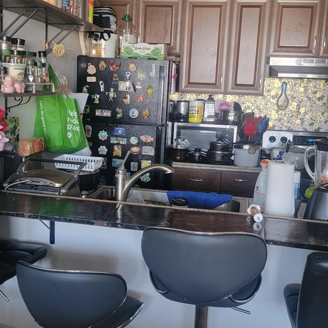 3312 Northside Dr Unit 407, Key West, FL 33040 - kitchen with under cabinet range hood, freestanding refrigerator, dark countertops, and backsplash