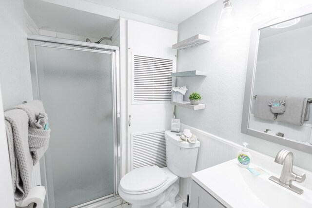 bathroom with vanity, a shower with door, and toilet