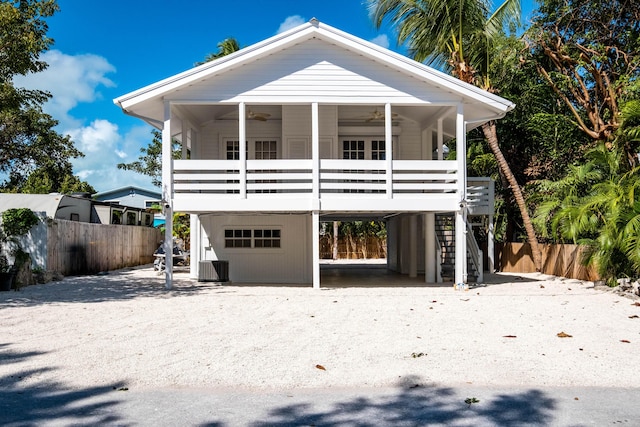 coastal home featuring ceiling fan, stairway, fence, central AC, and a carport