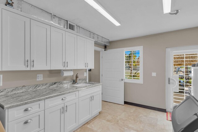 kitchen with white cabinetry, sink, and light stone counters