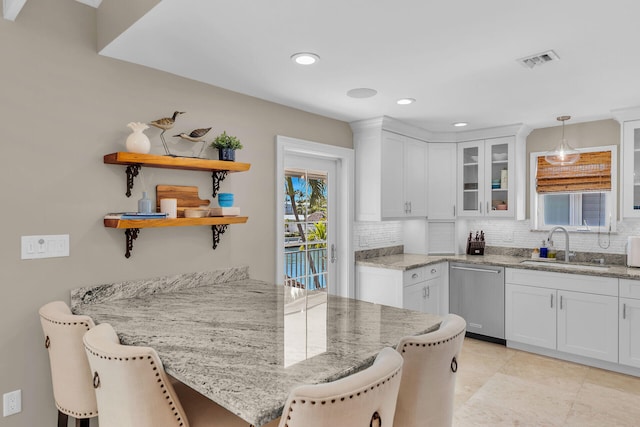 kitchen featuring decorative light fixtures, white cabinetry, sink, a kitchen bar, and stainless steel dishwasher