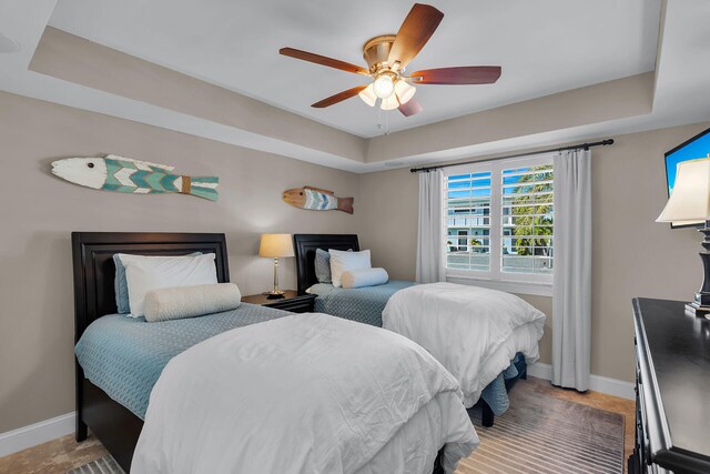 bedroom with a raised ceiling and ceiling fan