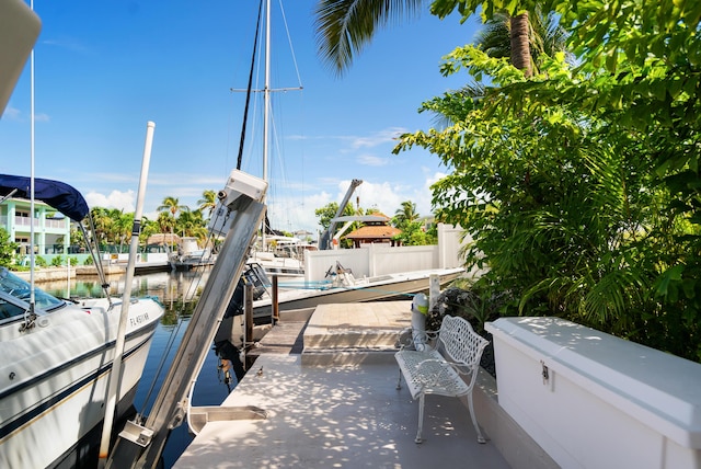 dock area featuring a water view, boat lift, and fence