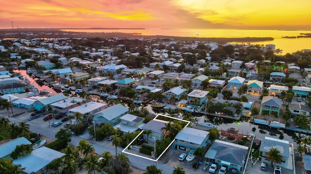 aerial view at dusk with a water view and a residential view