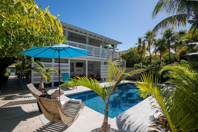 pool featuring a sunroom, stairs, and a patio