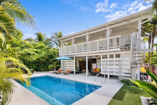 back of property with stairs, a patio, and an outdoor pool