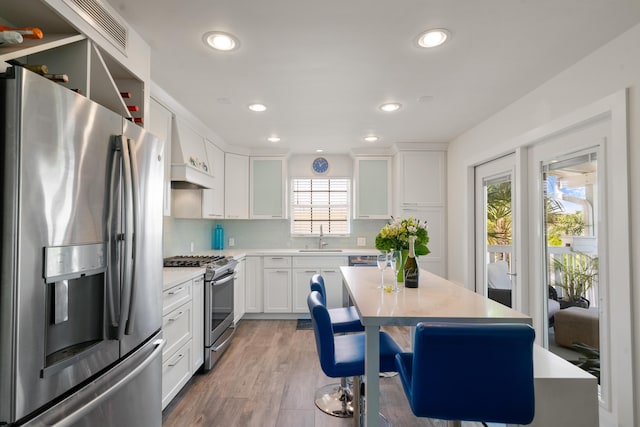 kitchen featuring stainless steel appliances, tasteful backsplash, light countertops, and white cabinets