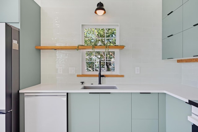 kitchen with a sink, freestanding refrigerator, decorative backsplash, dishwasher, and open shelves