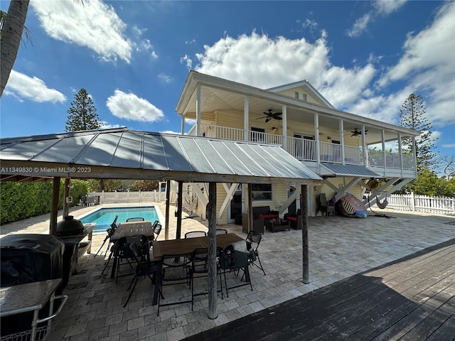 view of patio with outdoor dining space, stairway, a ceiling fan, fence, and a fenced in pool